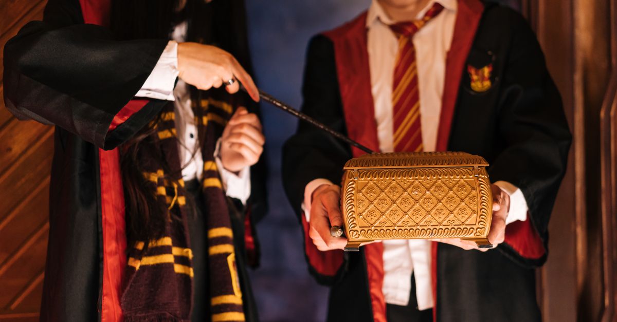 Two adults in wizard costumes interact with a magical box, evoking a fantasy realm.